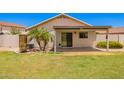 Well-maintained backyard with a covered patio, palm tree, and mature landscaping at 13824 N 148Th Ln, Surprise, AZ 85379