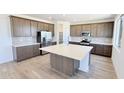 Spacious kitchen boasts stainless steel appliances, shaker cabinets, a stylish tile backsplash, and an expansive center island at 15159 W Gray Fox Trl, Surprise, AZ 85387