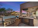 A covered outdoor kitchen features a built-in grill, bar area, refrigerator, and backyard views at 22233 N 54Th Way, Phoenix, AZ 85054