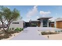 View of a contemporary home with a flat roof, stone and glass entry, and a spacious front driveway and desert landscaping at 3648 N Sky Point Cir, Mesa, AZ 85207