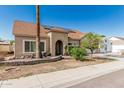 Attractive exterior view of home featuring a well-manicured landscape, an arched entryway, and a clear blue sky at 4207 W Soft Wind Dr, Glendale, AZ 85310