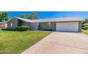 A single story home with a two car garage, privacy screen, and a large green front yard at 6127 N 16Th Pl, Phoenix, AZ 85016