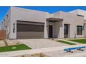 Modern home featuring desert landscaping, a gray two-car garage, and a geometric walkway at 10332 E Utah Ave, Mesa, AZ 85212