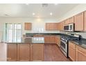 Well-lit kitchen with an island, stainless appliances, granite counters, and wood floors at 19432 W Morning Glory Dr, Buckeye, AZ 85326