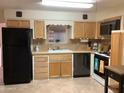 Functional kitchen featuring light wood cabinets, tile countertops, and a black appliance suite at 2405 N Eastwood Way, Mesa, AZ 85215