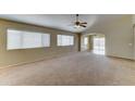 Spacious living area offering neutral carpeting, a ceiling fan, and sliding doors to the patio at 25729 W St Charles Ct, Buckeye, AZ 85326