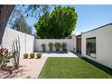 The backyard is beautifully landscaped with artificial grass, planters, pavers, and privacy wall at 4336 E Piccadilly Rd, Phoenix, AZ 85018