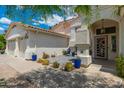Charming home with a cozy front patio featuring blue chairs, an ornate front door, and desert landscaping at 5510 W Arrowhead Lakes Dr, Glendale, AZ 85308