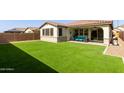 Spacious backyard with artificial turf, desert landscaping, and a covered patio for outdoor living at 6931 W Spur Dr, Peoria, AZ 85383