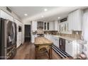 Bright kitchen featuring white cabinets, stainless steel appliances, an island, and hardwood floors, offering both style and functionality at 736 S Winthrop Cir, Mesa, AZ 85204