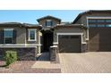 Beautiful single-story home with a brick driveway, stone accents, and a private gated entrance at 17427 W Hadley St, Goodyear, AZ 85338