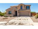 Two-story beige home featuring a two-car garage and desert landscaping on a sunny day at 18663 W Vogel Ave, Goodyear, AZ 85338