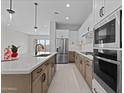 Modern kitchen featuring stainless steel appliances, two-toned cabinetry, quartz countertops, and a spacious island with a sink at 19321 W Luke Ave, Litchfield Park, AZ 85340