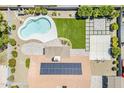 Aerial view of the backyard with a kidney-shaped pool, artificial turf, a covered patio, and solar panels at 625 E Silver Creek Rd, Gilbert, AZ 85296