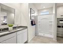Bright bathroom with dual sinks, granite counters, a shower with white tiling, and a window at 9943 S Desert View Dr, Apache Junction, AZ 85120