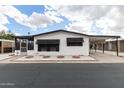 Charming exterior of a white single-story home with dark shutters and a carport at 11000 N 91St Ave # 101, Peoria, AZ 85345