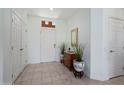 Bright foyer with neutral tile flooring, a decorative mirror, and ample closet space for storage at 16158 W Copper Point Ln, Surprise, AZ 85374