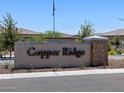 Community entrance sign for Copper Ridge featuring decorative stone and landscaping at 20795 N Roadrunner Ln, Maricopa, AZ 85138