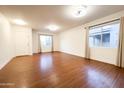 Spacious living room with hardwood flooring, two windows, neutral walls, and a ceiling fan at 22755 W Yavapai St, Buckeye, AZ 85326