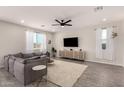 Bright living room features a ceiling fan, recessed lighting, plush sofa, and large windows with sheer curtains at 22962 N 182Nd Ln, Surprise, AZ 85387