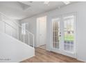 View of the living room with wood floors, a staircase, and double doors to the outside at 3511 E Baseline Rd # 1235, Phoenix, AZ 85042