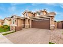 Home featuring a two car garage, stone facade, landscaped yard, and brick driveway for added curb appeal at 3637 E Ebano St, Gilbert, AZ 85295