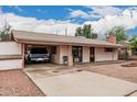 Single-story house with a long driveway leading to an open carport; front entrance has a small dog house at 4144 N 29Th Ave, Phoenix, AZ 85017