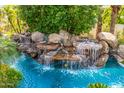 Close-up view of a waterfall cascading into the turquoise pool at 6112 E Jenan Dr, Scottsdale, AZ 85254