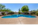 Freeform swimming pool with rock waterfall feature surrounded by desert landscaping and mature trees for a private backyard oasis at 9203 E Topeka Dr, Scottsdale, AZ 85255