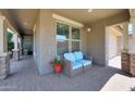 Inviting front porch featuring comfortable seating, decorative flower pots, and a view of the serene outdoor surroundings at 9750 E Radioactive Dr, Mesa, AZ 85212
