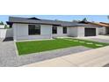 Front exterior view featuring updated white brickwork, dark roof, an attached garage, and a green synthetic front lawn at 1030 E Wescott Dr, Phoenix, AZ 85024