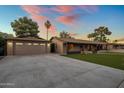 Charming home with a detached two car garage and a long driveway with lush green grass and sunset colored sky at 1640 E Solano Dr, Phoenix, AZ 85016