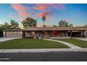 Charming single-story home with well-manicured lawn, welcoming walkway and palm tree under a colorful sunset sky at 1640 E Solano Dr, Phoenix, AZ 85016
