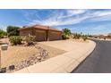 Charming home exterior with a three-car garage, desert landscaping, and mature trees at 17406 N Escalante Ln, Surprise, AZ 85374