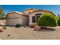 Charming single-story home featuring a two-car garage and desert landscaping at 20424 N 96Th Ln, Peoria, AZ 85382