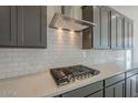 Close-up of a gourmet kitchen featuring a stainless steel range hood and sleek cooktop over bright white quartz countertops at 262 S 164Th Dr, Goodyear, AZ 85338