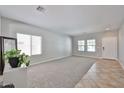 Inviting living room with neutral carpeting, two windows, and a white door at 30263 W Crittenden Ln, Buckeye, AZ 85396