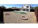 Spacious backyard featuring gravel, a putting green, patio, and multiple firepit areas, great for outdoor enjoyment at 37061 W Bello Ln, Maricopa, AZ 85138