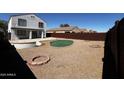 Wide backyard with a putting green, patio, gravel area, fire pit, and a fence surrounding the property at 37061 W Bello Ln, Maricopa, AZ 85138