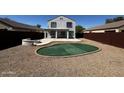 This house features a spacious backyard with gravel, a putting green, and a concrete patio for relaxing at 37061 W Bello Ln, Maricopa, AZ 85138