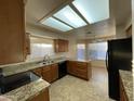 Well-lit kitchen featuring granite countertops, wooden cabinets, and black appliances at 4332 E Frye Rd, Phoenix, AZ 85048