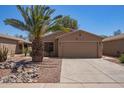 Desert-landscaped single-story home with a two-car garage and palm tree, presenting curb appeal at 43949 W Sagebrush Trl, Maricopa, AZ 85138