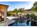 Inviting outdoor space with a covered patio, lush greenery, a pool, and picturesque views of the surrounding landscape at 5023 S Dusty Coyote Trl, Gold Canyon, AZ 85118