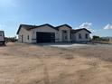 New construction home with neutral colored stucco, modern black garage door, and xeriscape landscaping at 11798 S 216Th Ave, Buckeye, AZ 85326
