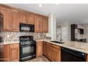 Traditional kitchen with granite countertops, backsplash, wood cabinets, and black appliances at 21059 E Pickett St, Queen Creek, AZ 85142