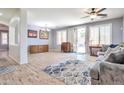 Bright living room with wood floors, a ceiling fan, and sliding glass doors to the backyard at 6027 N 132Nd Dr, Litchfield Park, AZ 85340