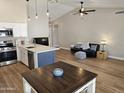 Spacious living room and kitchen area featuring vaulted ceilings, modern lighting, and wood flooring at 6873 S Lake Forest Ct, Chandler, AZ 85249