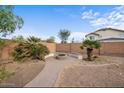 Backyard with a brick-paved path leading to a fire pit surrounded by bench seating at 7309 W Getty Dr, Phoenix, AZ 85043