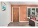 Cozy living room featuring an orange accent wall and hardwood floors at 8248 E Emelita Ave, Mesa, AZ 85208
