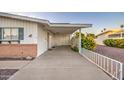 A covered carport provides ample parking space with a white railing and yellow flowers adding a touch of charm at 10620 W Clair Dr, Sun City, AZ 85351